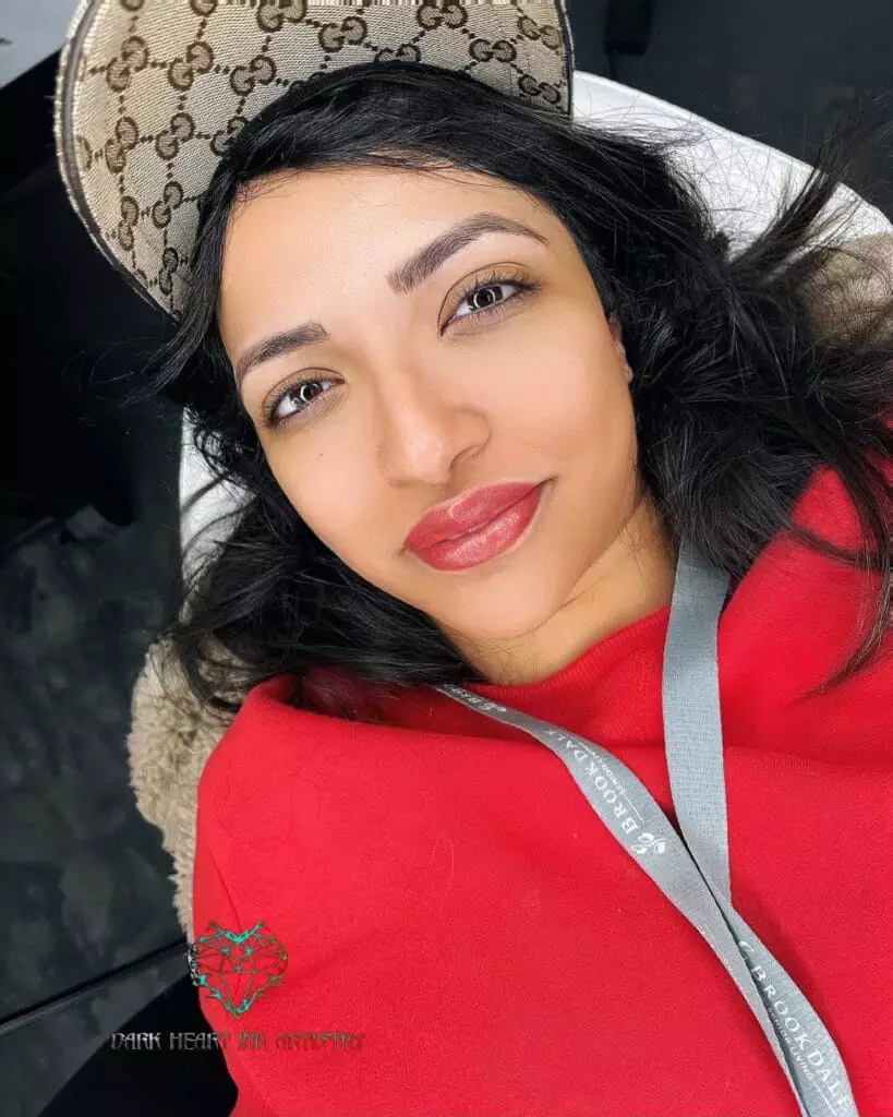 A woman in a red hat posing on a bed in an art gallery.