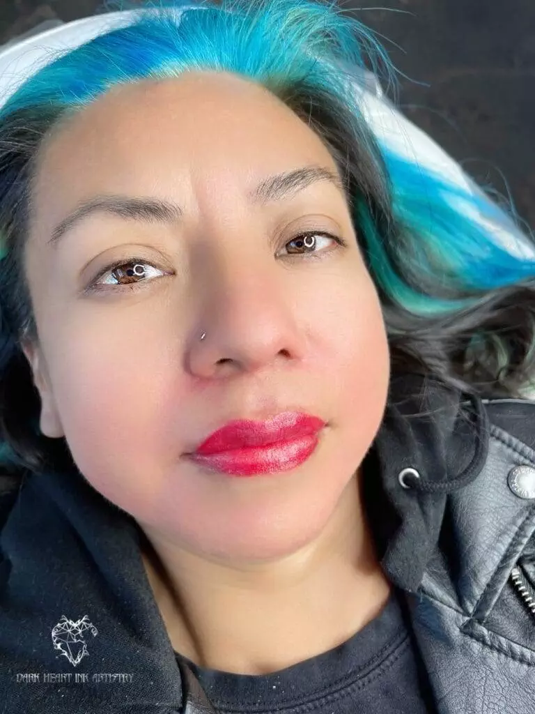 A woman with blue hair posing for a photo in a gallery.