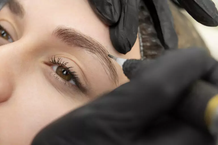 A woman getting her eyebrows tattooed in a salon gallery.