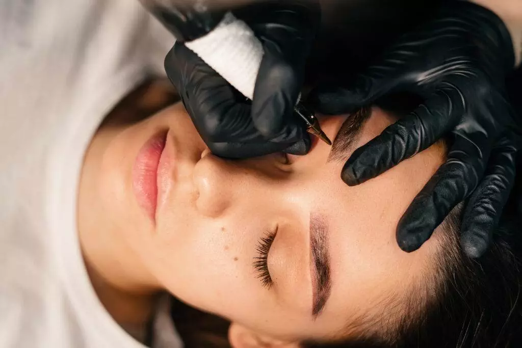 A woman undergoing eyebrow tattooing.