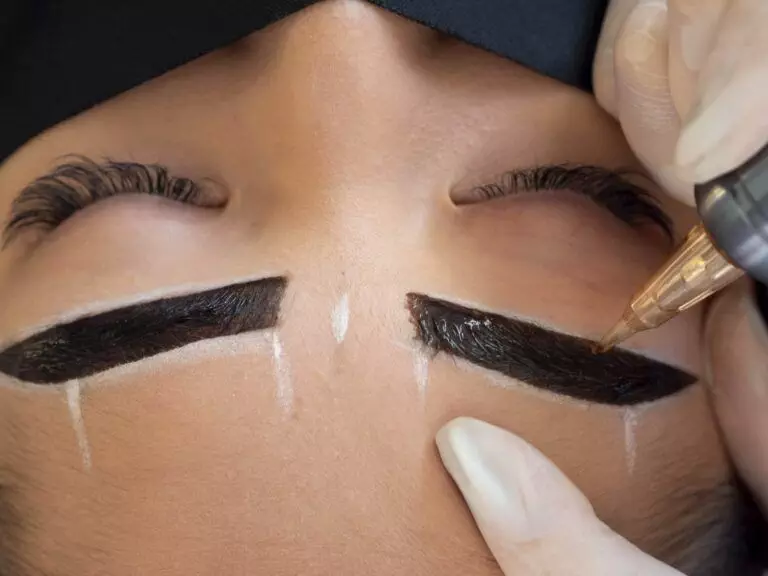 A person is undergoing a microblading procedure, which might be right for you. An artist is using a tool to apply pigment to the person's eyebrows, outlined with white markings.